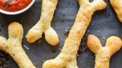 Cheesy Halloween Breadstick Bones shaped like skeleton bones on a plate.