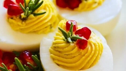 Plate of colorful Christmas deviled eggs garnished with herbs
