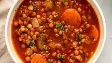 Bowl of classic lentil soup garnished with fresh herbs and vegetables