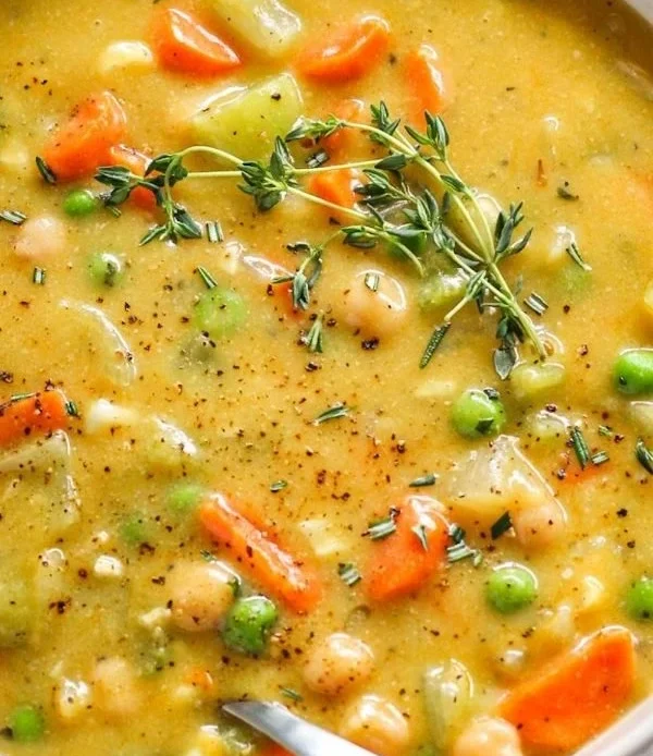 Bowl of comforting one-pot creamy vegetable soup with fresh vegetables and herbs.