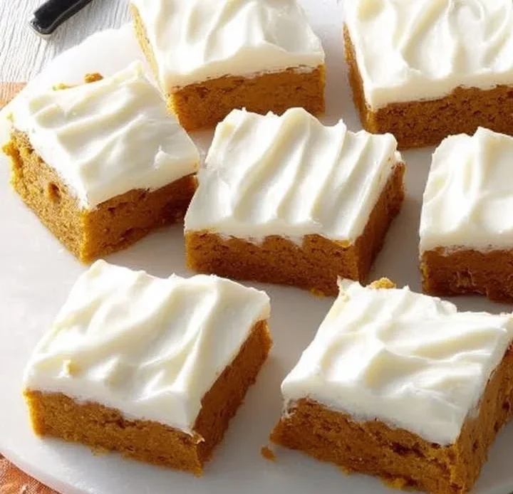 Cream cheese frosting spread over delicious pumpkin bars.