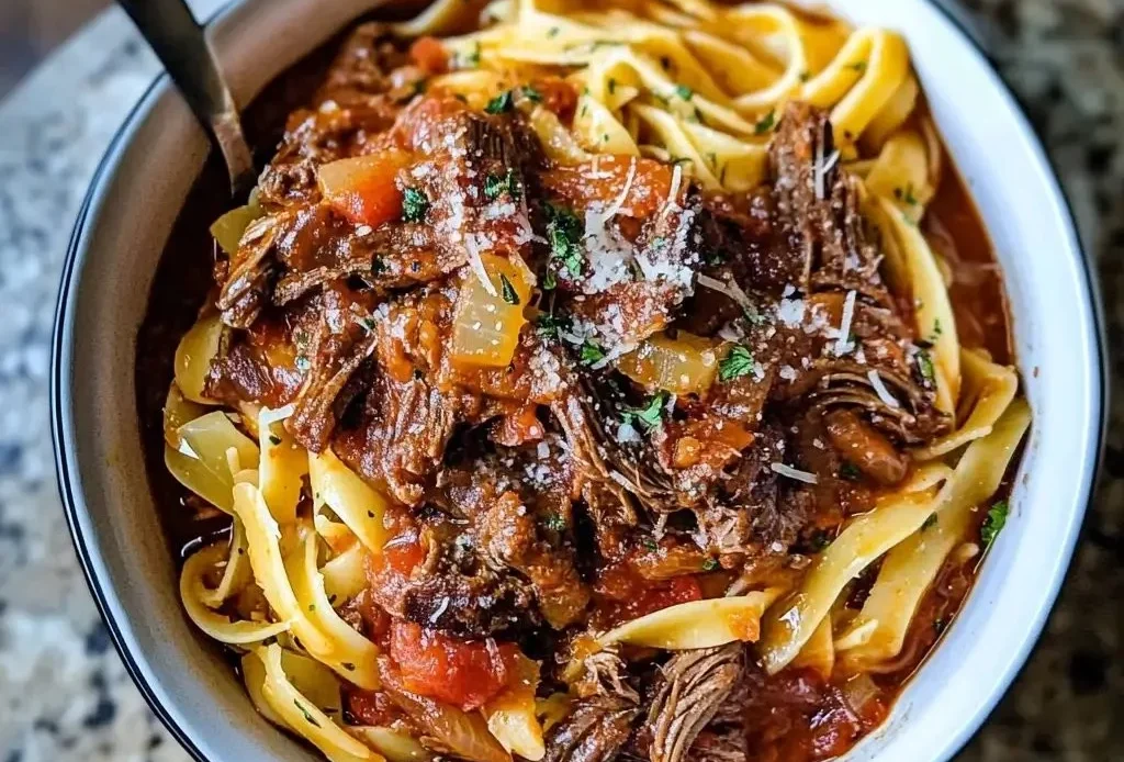Delicious slow cooker beef ragu served in a bowl with pasta and herbs.