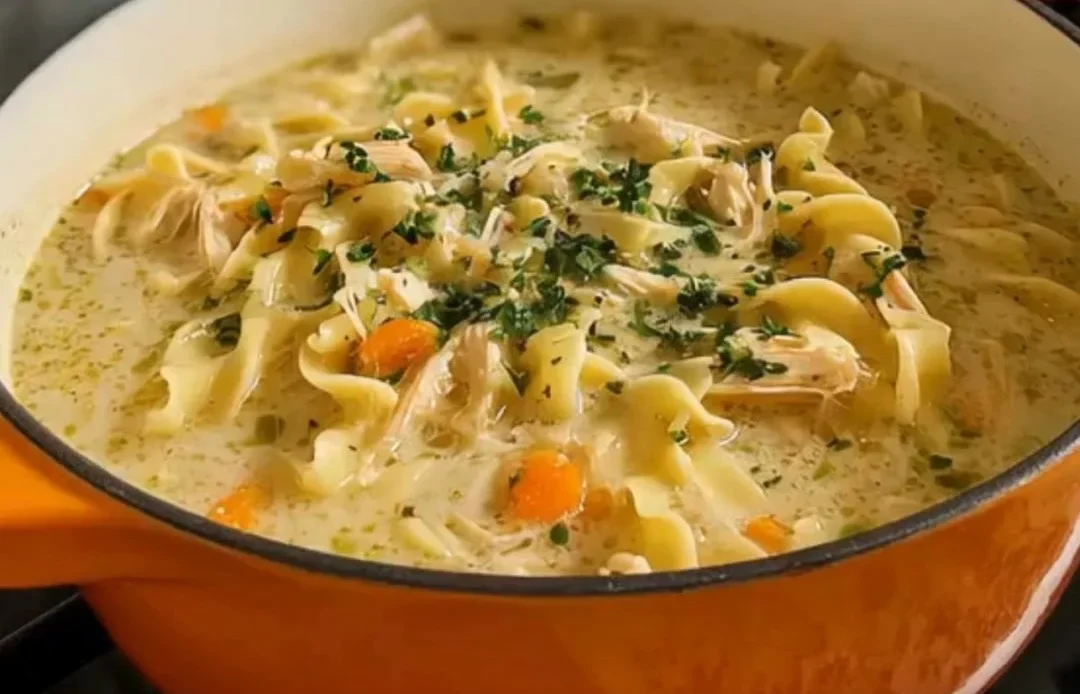 Bowl of creamy chicken noodle soup with vegetables and herbs