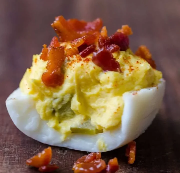 Plate of perfectly prepared deviled eggs garnished with paprika and herbs