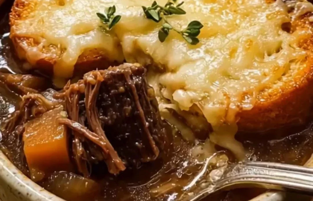Bowl of French onion short rib soup topped with melted cheese and fresh herbs.
