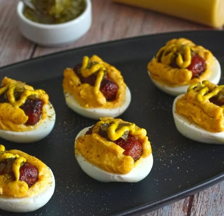 Hot dog deviled eggs topped with slices of hot dogs and paprika