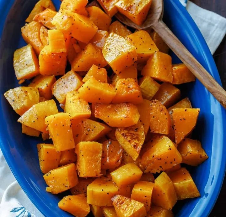 Oven-roasted butternut squash served on a plate, garnished with herbs.