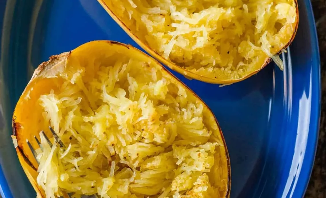 Plate of cooked spaghetti squash topped with fresh herbs and sauce