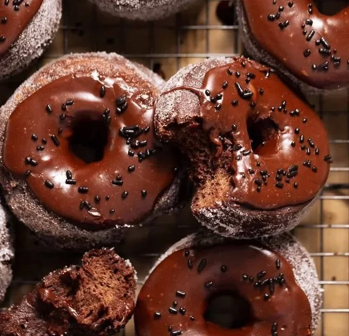 Delicious chocolate doughnuts topped with sprinkles on a plate.