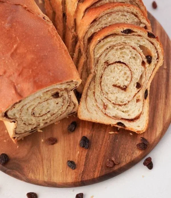 Freshly baked cinnamon raisin swirl sourdough bread on a wooden table.