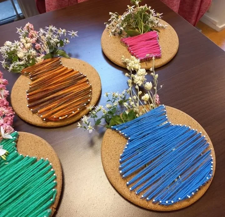 Artistic yarn flower vases crafted on round wooden boards