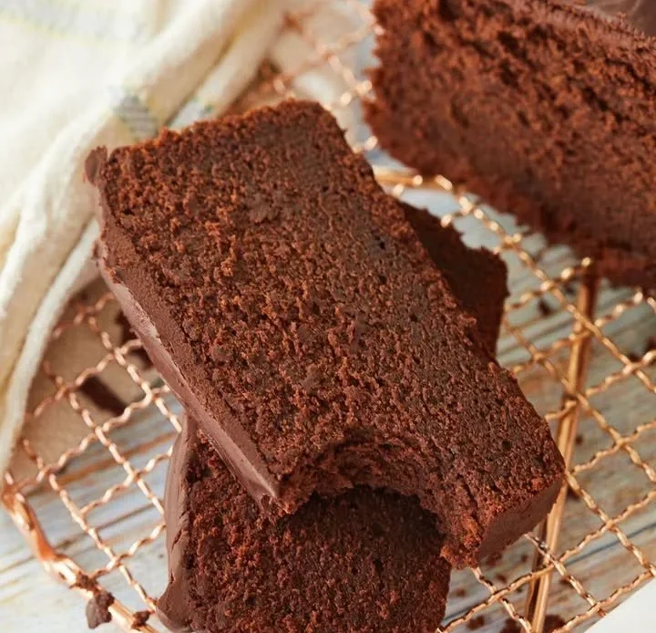 Decadent chocolate pound cake topped with chocolate icing on a white plate.