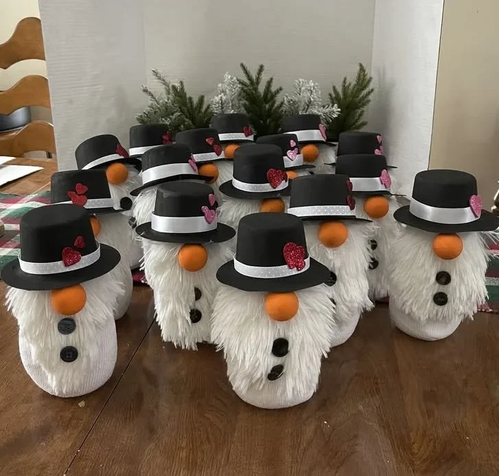 DIY snowmen made from fuzzy fabric with buttons and black hats and heart accents.