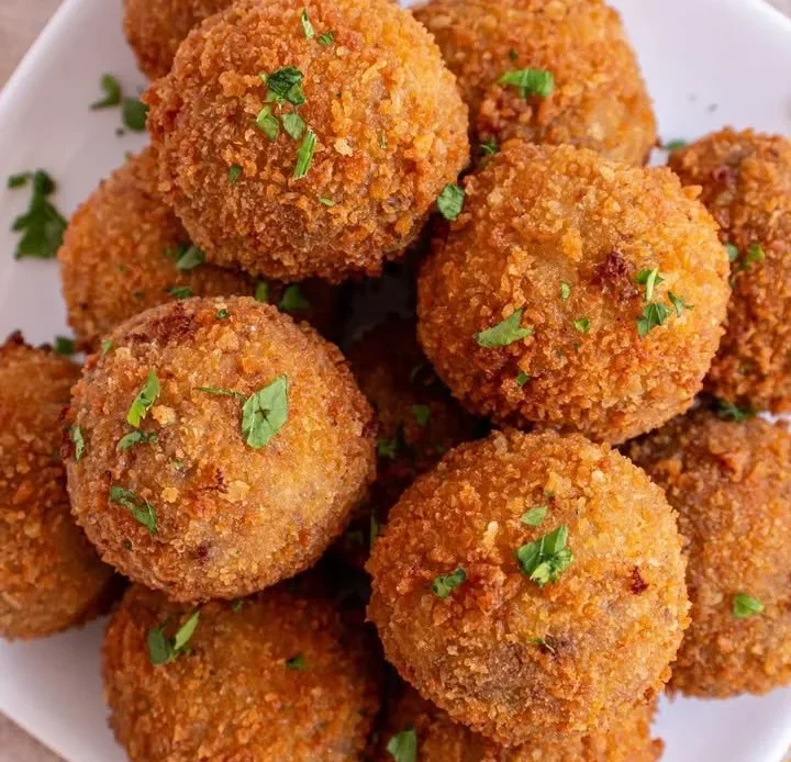 Plate of juicy meatballs served with marinara sauce and garnish